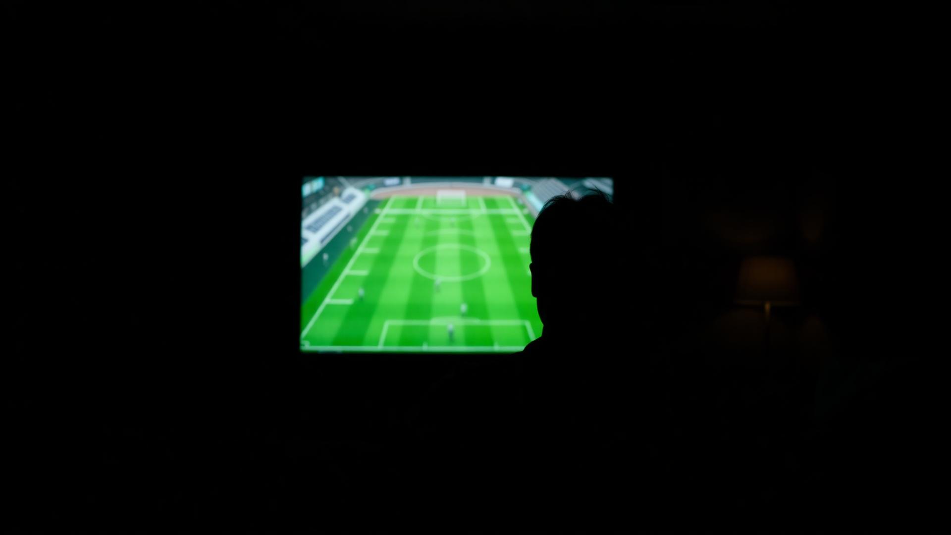 Man watching live sports on a large TV